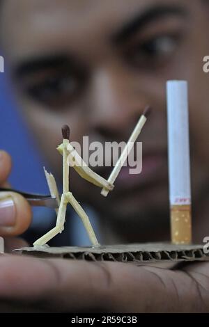 Bijoy Debnath, un artiste de 21 ans qui présente son œuvre d'art créée avec des allumettes et des cigarettes représentant un homme de allumettes tuant une cigarette avec une épée dans le cadre d'une campagne « cesser de fumer » à la veille de la « Journée mondiale sans tabac ». 31 mai est célébrée comme la Journée mondiale sans tabac pour sensibiliser à la consommation de tabac dans le monde entier. Agartala, Inde. Banque D'Images