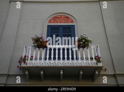 Façade traditionnelle avec une fenêtre voûtée, des volets en bois et un balcon en fonte avec des pots de fleurs en argile à Mazara del Vallo en Sicile. Banque D'Images