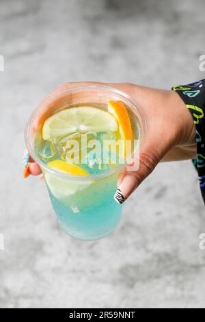 Femme tenant du thé à bulles avec de la limonade devant le mur en pierre grise Banque D'Images