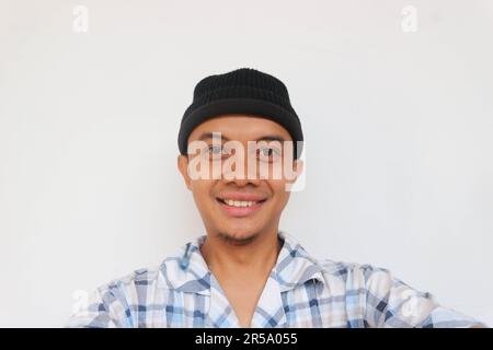 Homme portant un pyjama et un bonnet beanie souriant en regardant l'appareil photo. Isolé sur fond blanc Banque D'Images