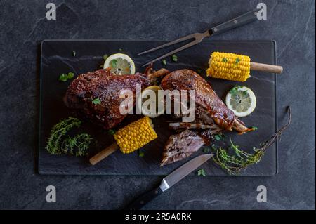 Plat à viande avec pattes de dinde grillées ou cuites au four. Servi avec du maïs sur le cop sur un plateau avec garniture sur fond sombre par le dessus Banque D'Images