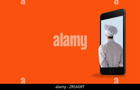 Le concept des applications de cuisine. Un chef dans un téléphone sur fond rouge avec un espace pour le texte. Applications mobiles pour chefs Banque D'Images