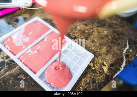 Verser le chocolat rose liquide dans un moule à barres - faire des barres de chocolat faites à la main. Photo de haute qualité Banque D'Images