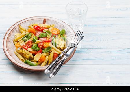 Une délicieuse assiette de pâtes italiennes ornée de tomates fraîches et de feuilles de basilic aromatiques. Avec espace de copie Banque D'Images