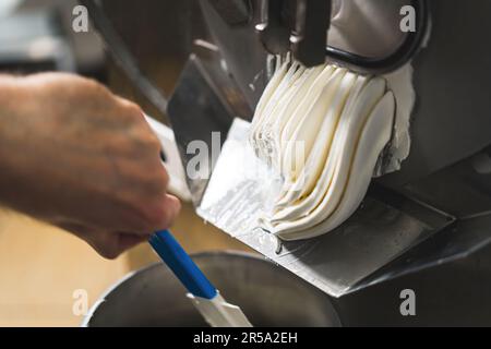 De la glace au chocolat sortant de la machine à surgélation en lot dans le récipient. Photo de haute qualité Banque D'Images