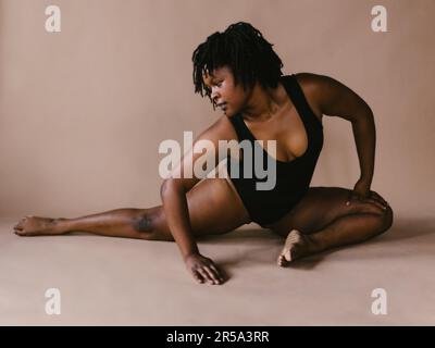 Femme danseuse noire en demi-fente de danse extensible pose en studio Banque D'Images