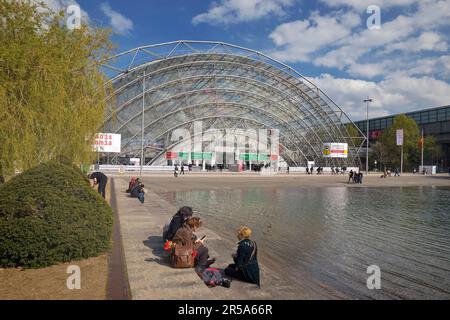 Salle de verre avec les gens au bassin d'eau en face de l'entrée principale de la Foire du livre de Leipzig, Nouvelle foire, Allemagne, Saxe, Leipzig Banque D'Images