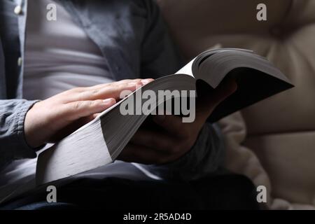 Homme lisant la sainte Bible sur le canapé, gros plan Banque D'Images