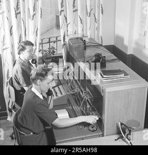 Téléphonie dans le 1950s. Deux femmes travaillant à un standard téléphonique comme opérateur. Un système de communication téléphonique qui a été actionné manuellement où les appels entrants ont été renvoyés et redirigés vers un autre numéro de téléphone par l'opérateur, dans ce cas localement dans le bâtiment desservant une entreprise ou une organisation avec de nombreuses lignes téléphoniques internes. L'opérateur du standard peut prendre des messages et vous mettre en attente si la ligne était occupée. Suède 1944. Kristoffersson réf. K66-1 Banque D'Images