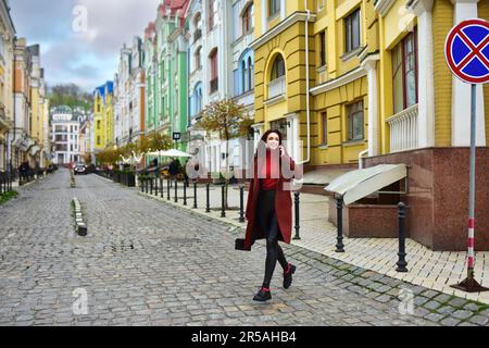 Une femme d'affaires élégante souriante court de l'autre côté de la rue. Une femme marche dans la rue avec le sourire. Banque D'Images