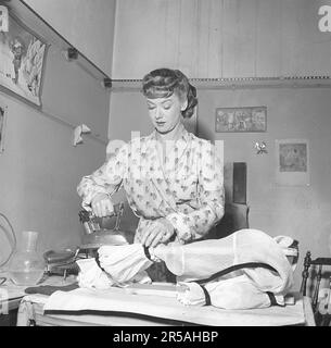 Repassage dans le 1950s. Une femme a vu repasser ses vêtements. Elle est actrice Sonja Wigert 1913-1980. Suède 1951. Kristoffersson réf. BE70-3 Banque D'Images