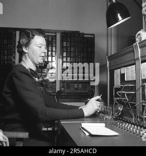 Téléphonie dans le 1950s. Une femme travaillant à un standard téléphonique comme opérateur. Un système de communication téléphonique qui a été actionné manuellement où les appels entrants ont été renvoyés et redirigés vers un autre numéro de téléphone par l'opérateur, dans ce cas localement dans le bâtiment desservant une entreprise ou une organisation avec de nombreuses lignes téléphoniques internes. L'opérateur du standard peut prendre des messages et vous mettre en attente si la ligne était occupée. Suède 1942. Kristoffersson réf. A129-2 Banque D'Images