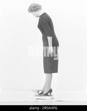 Femme dans les 1950s. Elle est debout et se pèse sur une balance. Suède mars 1959 Banque D'Images