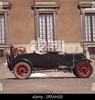 L'ancienne voiture. Un homme dans une ancienne tenue de conducteur typique avec une casquette en cuir, des friandises, une veste en cuir et des gants dans sa voiture Ford vintage, photographiée à l'extérieur du château royal de Stockholm. Suède 1960s. Banque D'Images