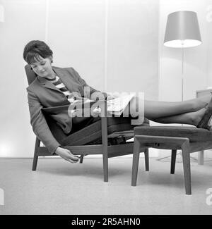 Décoration de la maison du 1960s. Une femme est assise confortablement dans une chaise pendant l'exposition annuelle de meubles organisée par Svensk Form 1963. Fauteuil réglable avec repose-pieds. Suède 1963 Banque D'Images