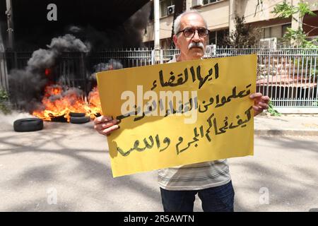 Un homme proteste contre le gouverneur de la Banque centrale libanaise Riad Salameh au Palais de Justice, Beyrouth, Liban, 1 juin 2023. L'affiche se lit comme suit : « les juges libanais apprennent de vos homologues français à poursuivre les criminels et les voleurs ». Le même jour, le Vice-Premier Ministre libanais Saade Chami a demandé la démission de Salameh après que le Gouvernement libanais ait reçu deux avis rouges d'Interpol pour lui. Selon des sources judiciaires, les avis faisaient suite à des mandats d’arrêt émis contre Salameh par des juges français et allemands pour des accusations de blanchiment d’argent, de fraude, de détournement de fonds et d’enrichissement illicite. Salame Banque D'Images