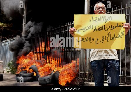 Un homme proteste contre le gouverneur de la Banque centrale libanaise Riad Salameh au Palais de Justice, Beyrouth, Liban, 1 juin 2023. L'affiche se lit comme suit : « les juges libanais apprennent de vos homologues français à poursuivre les criminels et les voleurs ». Le même jour, le Vice-Premier Ministre libanais Saade Chami a demandé la démission de Salameh après que le Gouvernement libanais ait reçu deux avis rouges d'Interpol pour lui. Selon des sources judiciaires, les avis faisaient suite à des mandats d’arrêt émis contre Salameh par des juges français et allemands pour des accusations de blanchiment d’argent, de fraude, de détournement de fonds et d’enrichissement illicite. Salame Banque D'Images