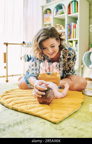 Bonne jeune mère s'habiller petit bébé Banque D'Images