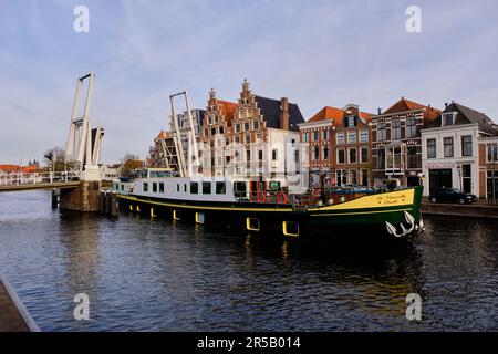 Haarlem, pays-Bas - 11 avril 2022: Barge passant sous le pont-plan surélevé Gravestenen sur la rivière Spaarne avec maisons à pignon en arrière-plan. Banque D'Images