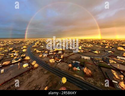 Cette image vibrante capture un arc-en-ciel époustouflant qui s'étend sur le ciel, au-dessus d'un paysage urbain animé Banque D'Images