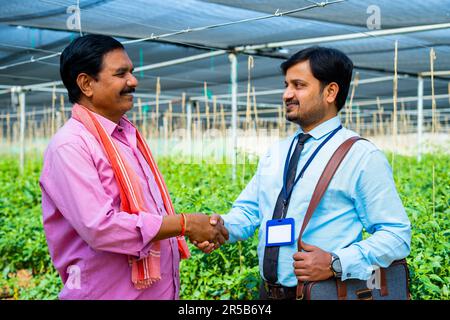 Un agriculteur indien heureux salue l'agent bancaire à Greenhouse en serrant la main - concept de soutien financier, de conseiller et d'expertise Banque D'Images