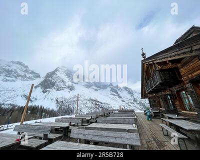 Une ambiance d'hiver tranquille avec une sélection de bancs en bois devant un bâtiment rustique en bois, blanchi dans une couche de neige blanche et éclatante Banque D'Images