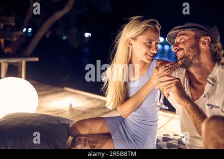 flirter sur la nuit de la lune. Un jeune couple aimant qui apprécie le vin lors d'une soirée romantique Banque D'Images