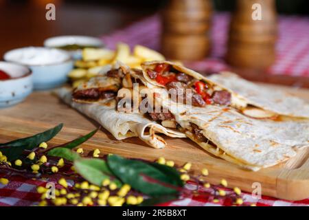 Gros plan de fajitas au poulet coloré servi sur un plateau en bois rustique, parfait pour un repas sain et délicieux Banque D'Images