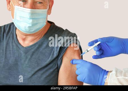 Médecin vaccinant l'homme supérieur en clinique. Vaccination des personnes âgées. Injection du vaccin contre le coronavirus MPOX à COVID19, grippe chez un homme mature 60s. Face Banque D'Images