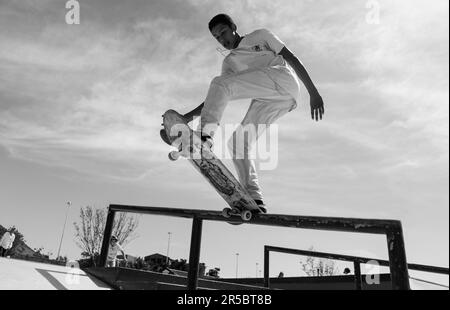 Un jeune patineur masculin exécute un tour audacieux tout en exécutant une ollie au-dessus d'un rail dans un environnement urbain Banque D'Images