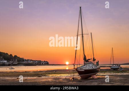 Plage d'Insow le dernier jour de mai. Le soleil touche l'horizon, comme à travers l'estuaire de la rivière Torridge, les lumières s'allument à Appledore, dans le nord du Devon. Banque D'Images