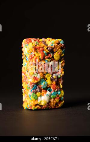 Gros plan d'une barre de bonbons recouverte d'une variété de céréales et de grains, avec quelques-uns éparpillés en arrière-plan Banque D'Images