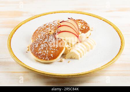Crêpes avec fruits sur une assiette blanche. Petit déjeuner savoureux. Banque D'Images
