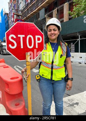 Une jeune femme travaillant pour une entreprise de construction dirige le trafic en passant par un grand projet de construction d'appartements dans le quartier de Windsor Terrace à Brooklyn, New York. Banque D'Images