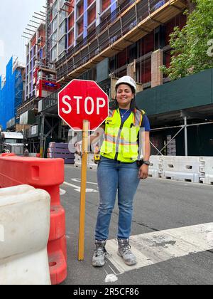 Une jeune femme travaillant pour une entreprise de construction dirige le trafic en passant par un grand projet de construction d'appartements dans le quartier de Windsor Terrace à Brooklyn, New York. Banque D'Images