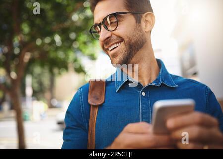 Je suis toujours de bonne humeur. un bel homme utilisant son téléphone portable pendant qu'il est en ville. Banque D'Images