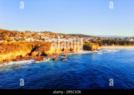 Côte de grès à flanc de falaise avec grottes marines dans la ville côtière de Caves Beach en Australie - vue aérienne sur le paysage depuis la mer. Banque D'Images