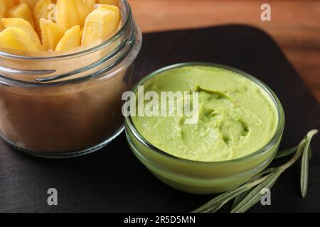 Plateau de service avec frites, sauce guacamole et romarin sur table en bois, en gros plan Banque D'Images