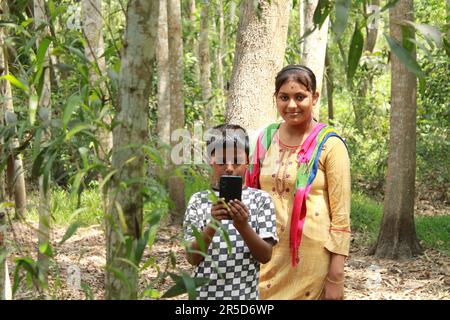 Indien Rural garçon et fille utilisant le téléphone portable à l'extérieur. Banque D'Images