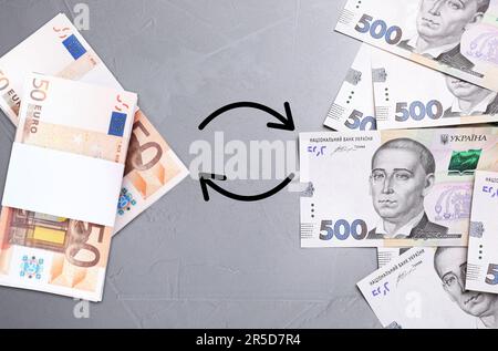 Bureau de change. Entourez les flèches entre hryvnias et les billets en euros sur fond gris, à plat Banque D'Images