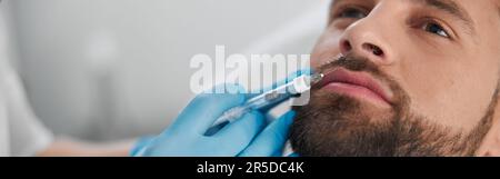 L'homme attrayant avec la barbe subit une procédure d'augmentation de la lèvre avec le cosmétologue en clinique Banque D'Images