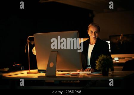 Je ne me dérange pas de mettre des heures supplémentaires pour satisfaire les clients. une femme d'affaires mûre travaillant tard au bureau. Banque D'Images