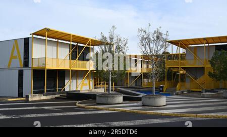 Une collection de bâtiments modernes blancs et jaunes en fer ondulé à l'université de Monash, avec de grandes lettres sur le côté Banque D'Images