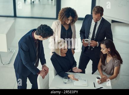 Passer en revue les objectifs standard et en définir de nouveaux. un groupe de collègues collaborant sur un projet dans un bureau moderne. Banque D'Images