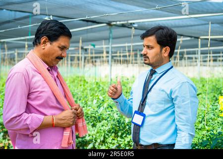Banquier indien donnant l'avertissement à l'agriculteur de ne pas payer le prêt ou le remboursement de la dette à l'agriculture serres - concept de problème financier, échéance et Banque D'Images