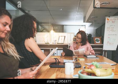 Prendre un moment pour lire le briefing. un groupe diversifié d'hommes d'affaires assis ensemble au bureau et planifiant une réunion. Banque D'Images