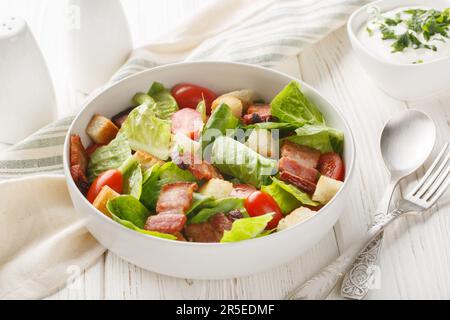 La salade BLT comprend une vinaigrette maison de ranch, du bacon croustillant, des croûtons, de la laitue et des tomates sur l'assiette de la table. Horizontale Banque D'Images