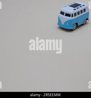 La fourgonnette bleue et blanche sur fond gris se déplace du coin supérieur droit. Copier l'espace. Concept de vie de fourgonnette minimaliste. Banque D'Images