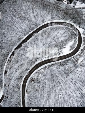 Routes d'hiver sinueuses depuis une vue plongeante. Cette route est dans une forêt. Paysage enneigé incroyable d'en haut Banque D'Images