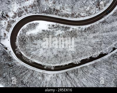 Routes d'hiver sinueuses depuis une vue plongeante. Cette route est dans une forêt. Paysage enneigé incroyable d'en haut Banque D'Images